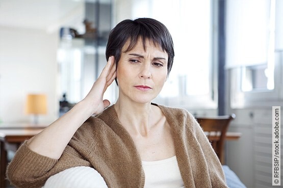 Frau hält sich die Hand ans Ohr: Ist eine Heilung vom Tinnitus möglich?