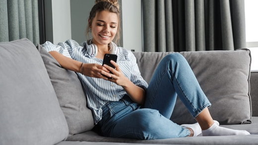Frau mit Smartphone: Sie hat Tinnitus und vereinbart eine Videosprechstunde mit einem Arzt oder einer Ärztin.