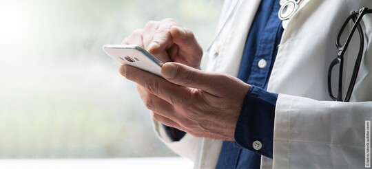 Arzt hält Handy in der Hand und testet die Kalmeda Tinnitus-App.