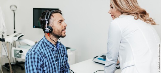 Tinnitus-Behandlung: Mann mit Kopfhörern bei der HNO-Ärztin.