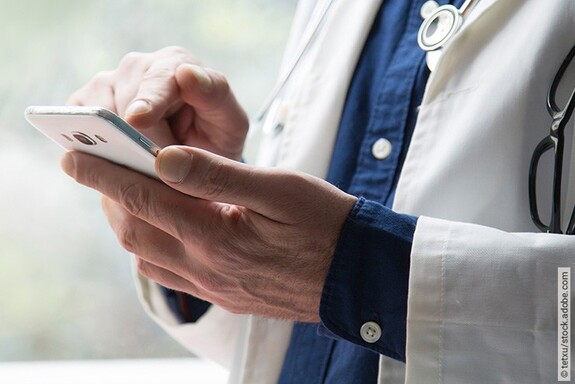 Arzt hält Handy in der Hand und testet die Kalmeda Tinnitus-App.