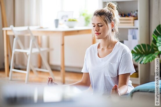 Frau macht Yoga-Übungen um mehr Ruhe in ihren Alltag zu bekommen und somit eine Heilung von Tinnitus zu begünstigen.