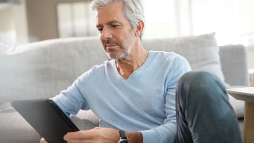 Mann mit Tablet: Er hat Tinnitus und sucht einen Arzt oder eine Ärztin vor Ort, um Zugang zur Kalmeda App zu bekommen.