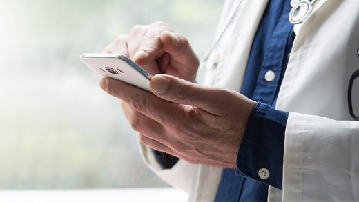 Arzt hält Handy in der Hand und testet die Kalmeda Tinnitus-App.