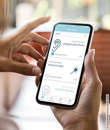 Eine Frau hält ein Handy in der Hand und nutzt Kalmeda Tinnitus-App.