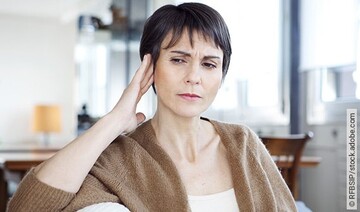 Frau hält sich die Hand ans Ohr: Ist eine Heilung vom Tinnitus möglich?