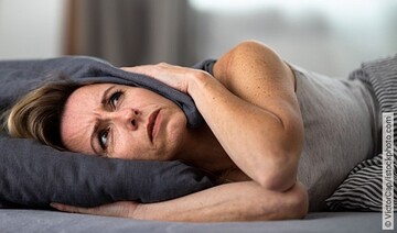 Frau leidet unter Tinnitus und bedeckt ihre Ohren mit Kissen.